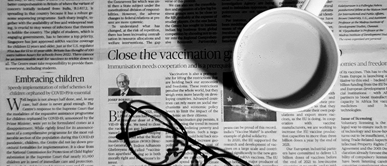 Black and white image of a newspaper with a mug and glasses on top of the newspaper